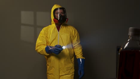 hombre vestido con traje de materiales peligrosos explora una habitación llena de humo