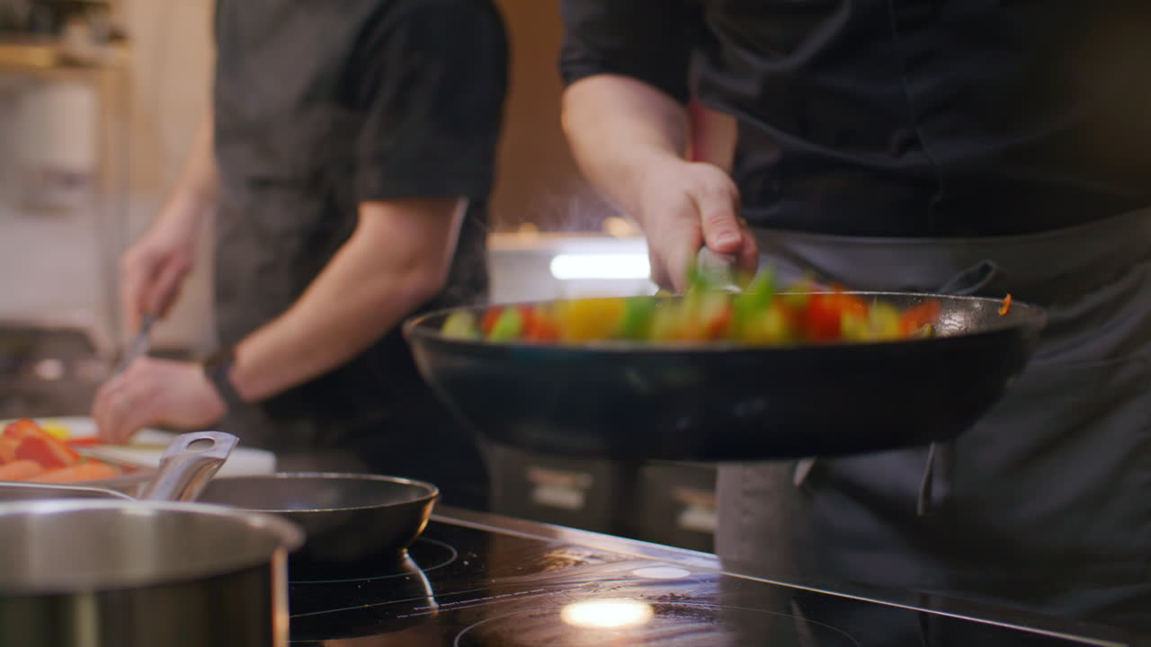 Chef del ristorante che aggiunge sale e salta verdure miste in padella