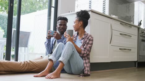 video of happy african american couple drinking coffee and talking at home