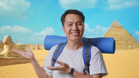 close up of asian male hiker with mountaineering backpack smiling and pointing to side while traveling in pyramid of giza
