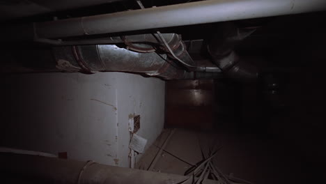 metal pipes of diverse width on the ceiling of a basement. dark premise of an old building with no light.