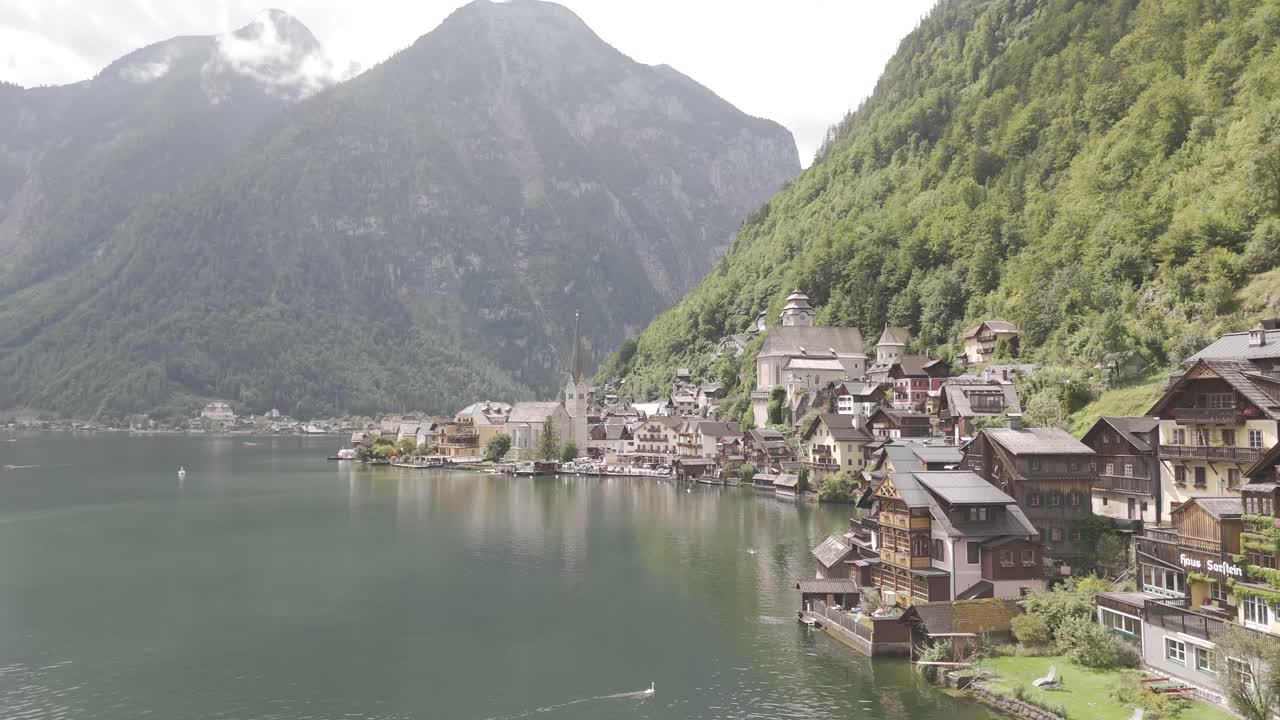 Aerial view of Hallstatt, Austria, captured by drone, showcasing its picturesque lakeside homes, majestic mountains, and the unique charm of this enchanting alpine village.
