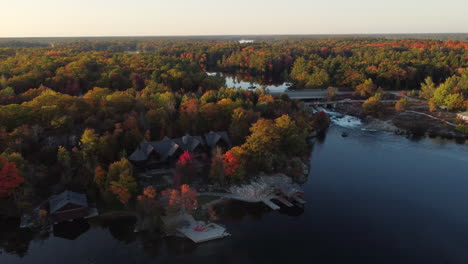 Aerial-over-dense-green-nature-reserve-around-beautiful-lake-and-cottages,-on-an-unexplored-land