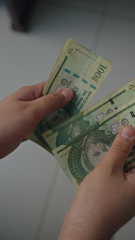 vertical close up of male hands counting a stack of one hundred thousand guaraníes pyg banknotes