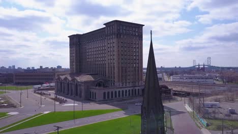 aerial of the exterior of the abandoned central train station in detroit michigan includes church steeple foreground