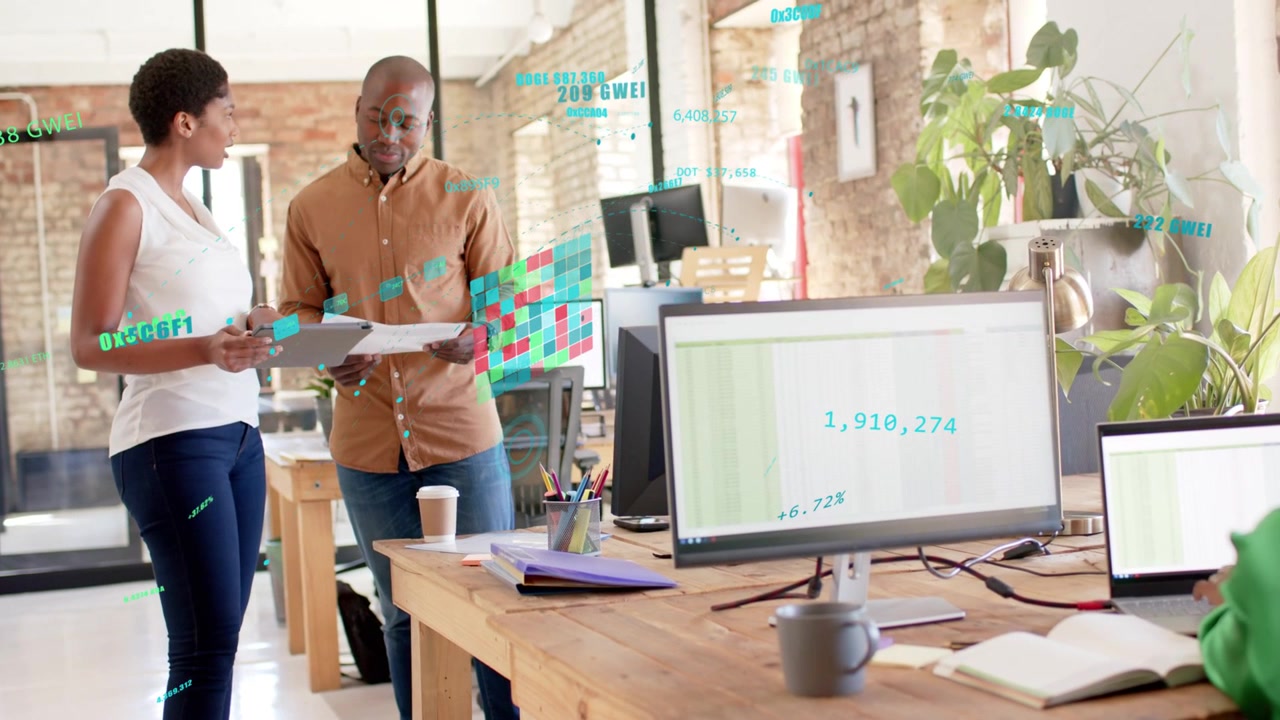 Colleagues holding report and pointing, reviewing business numbers while monitor data animating