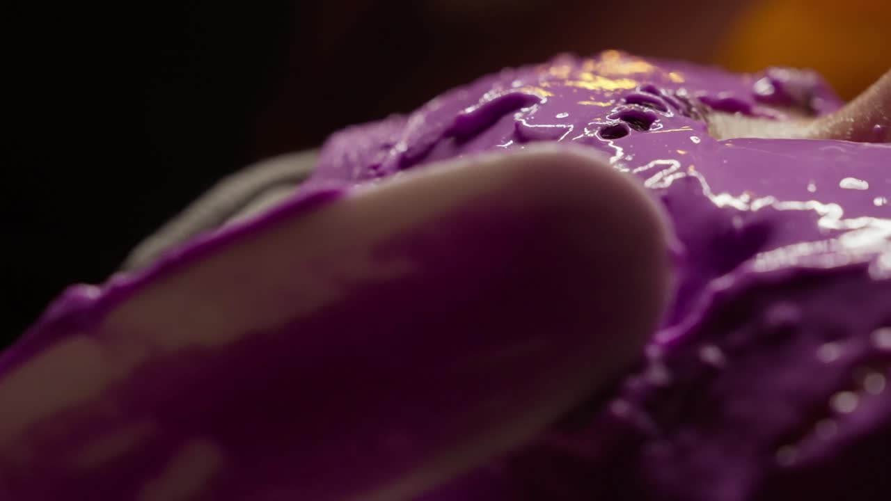 Primo piano di una maschera viso viola che viene applicata sul viso di una persona