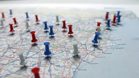 focus pulls onto red white and blue pins placed marking cities on a us map focused on the east coast on a map of the usa