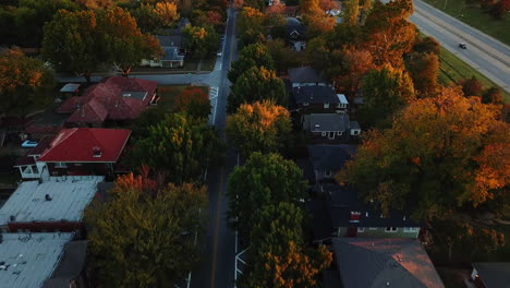 Aerial-shot-overhead-a-residential-street-with-autumnal-trees-alongside-a-highway