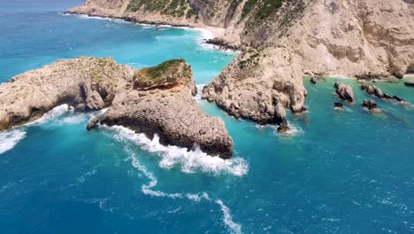 Orbiting-drone-shot-of-the-boulders-in-the-rocky-shoreline-of-Petanoi-Beach,-located-in-the-island-of-Kefalonia-in-Greece