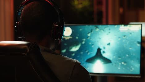 gamer using headphones to discuss with mates while playing sf game, close up