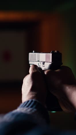 vertical video man in shooting gallery using gun, looking at results on moving target, closeup