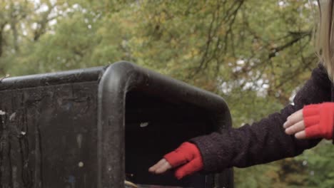 woman disposing plastic garbage in park bin