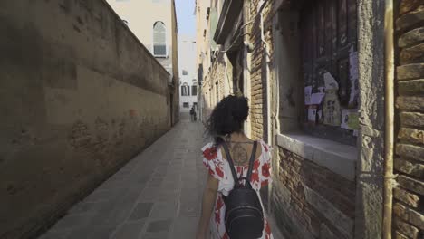 Chica-Vestida-De-Blanco-Con-Una-Mochila-Caminando-Por-Una-Calle-Estrecha-A-Cámara-Lenta