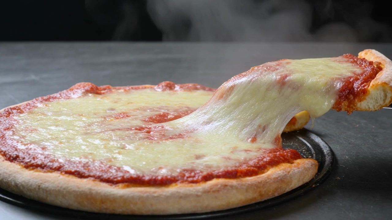Spatola di metallo che scivola sotto una fetta, pizza sul bancone della cucina che tira lunghi fili di formaggio per essere servita.