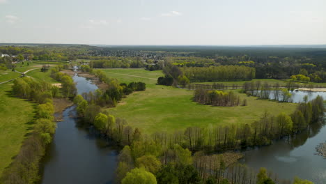 drone view over idyllic park area with growing trees along shoreline of lake during sunny autumn day in myślęcinek, poland