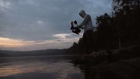 a person filming a lake landscape with a cinema camera in norway during sunset