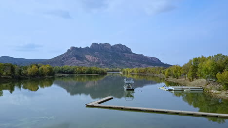 Aerial-shot-dolly-out-in-small-lake-with-boat-and-mountain-in-the-horizon,-South-of-France