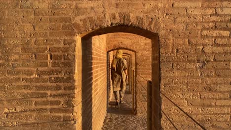 a beautiful persian girl woman super model is walking through corridor in si-o se pol esfahan the cultural historical capital of safavid empire brick architecture design on zayande roud river in iran