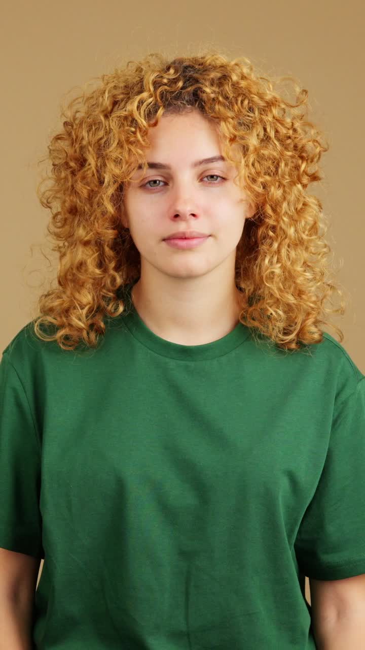 Woman with curly red hair expressing emotion with closed eyes