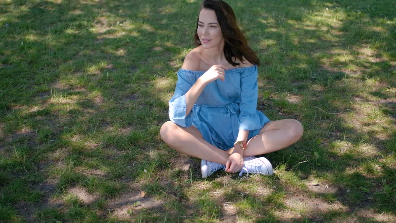 공원에 앉아 파란 드레스에 매력적인 갈색 머리 여자의 초상화