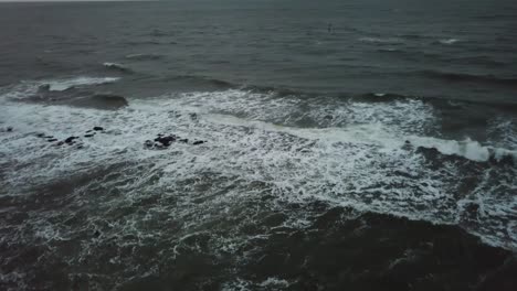 Drone-aerial-over-ocean-Melbourne-wavy-windy-cloudy-man-swimming-before-sunrise