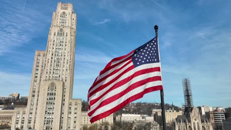 american flag waving beside cathedral of learning at university of pittsburgh in pennsylvania