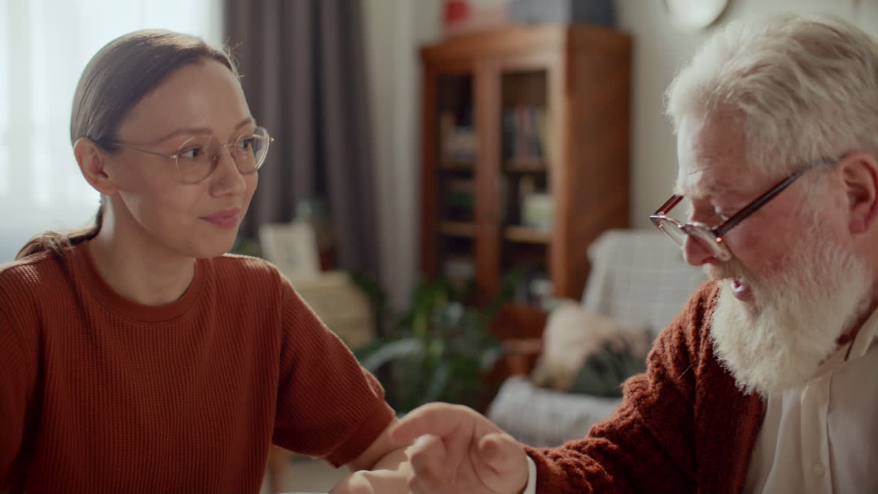 Elderly Man Speaking with Young Daughter over Cup of Tea at Home