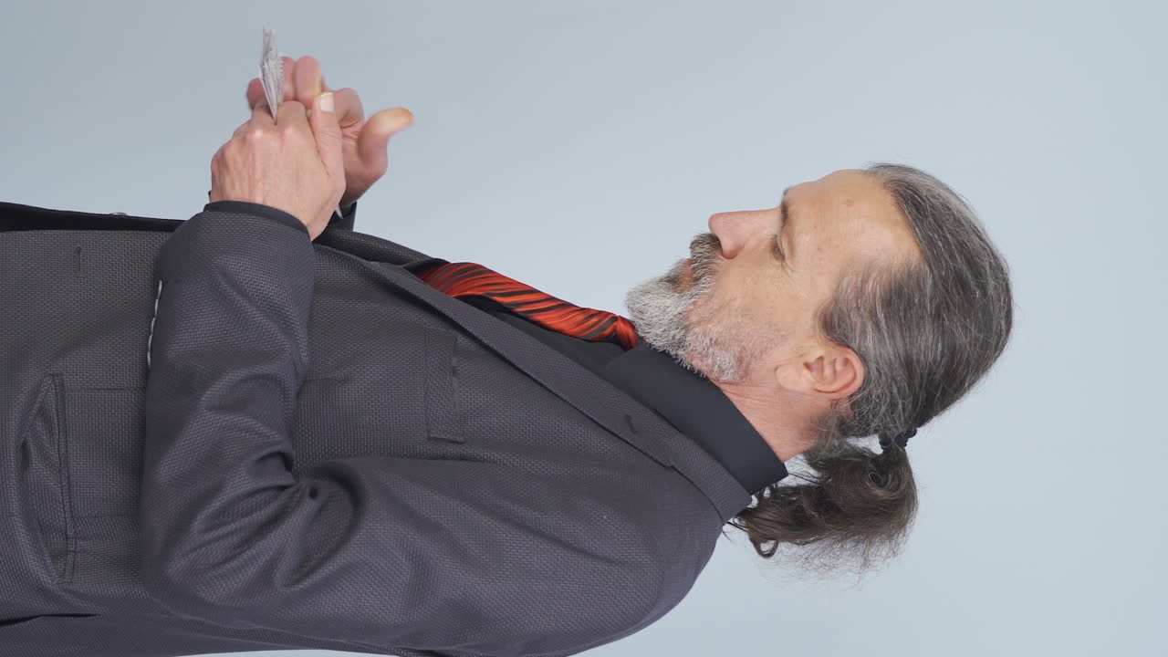 Video verticale di uomo d'affari anziano che conta i soldi guardando la telecamera