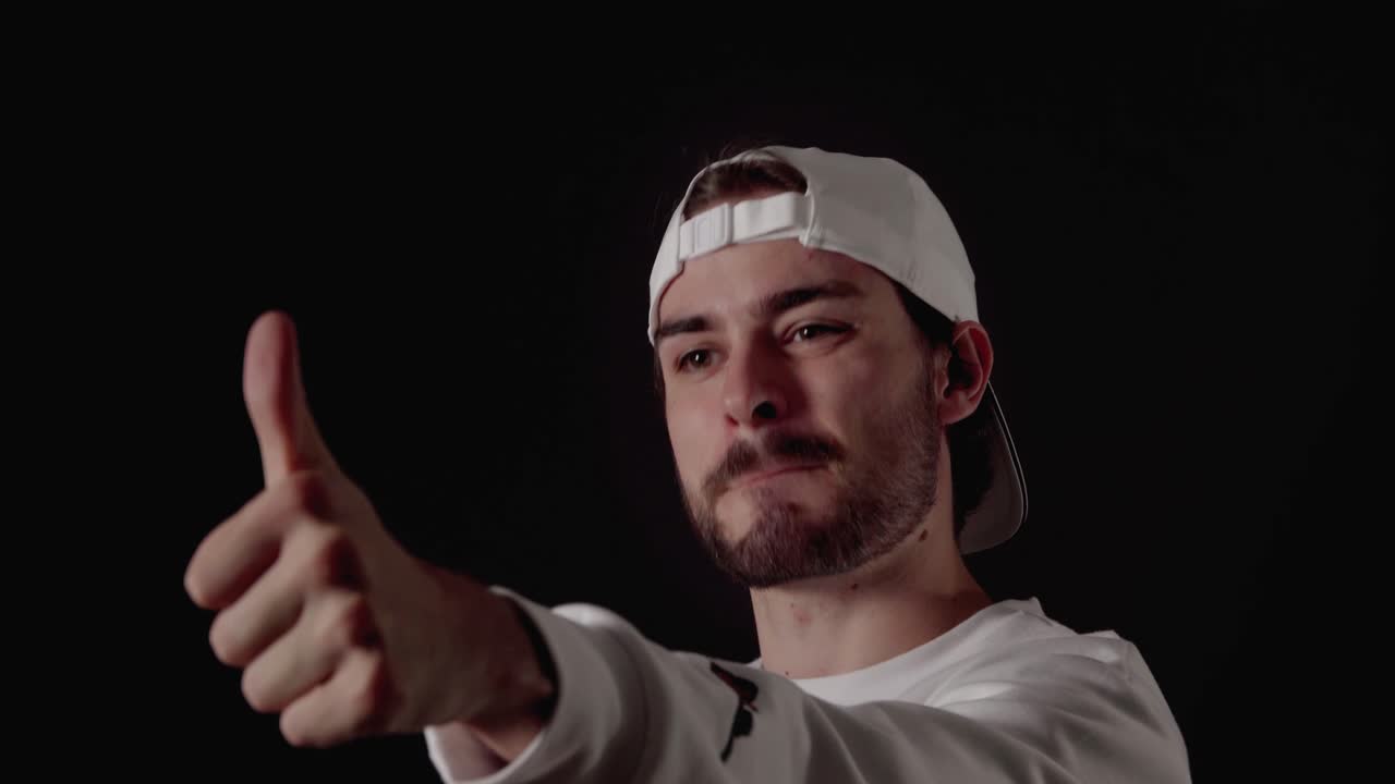 hombre moderno de 20 años dando pulgares hacia arriba, gesto agradecido, cerca, fondo negro