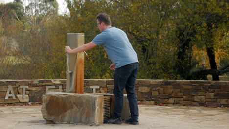 Man-pumps-a-mineral-water-fountain-and-drinks-from-his-hands