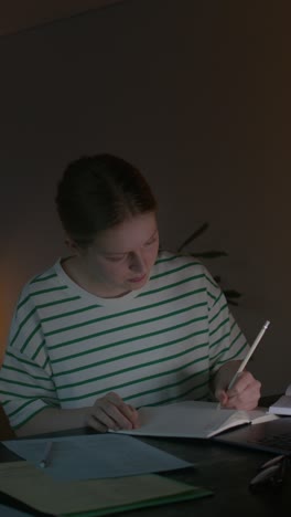 una mujer joven estudiando hasta tarde en la noche.