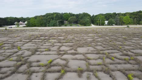 stormy overcast day over a cement parking lot overgrown with weeds