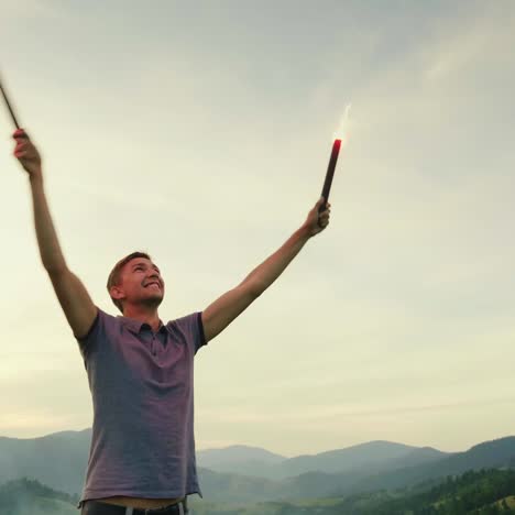 a man in the mountains signals with hand fireworks looks up