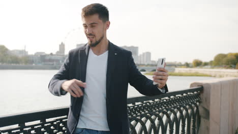 man excitedly using smartphone outdoors
