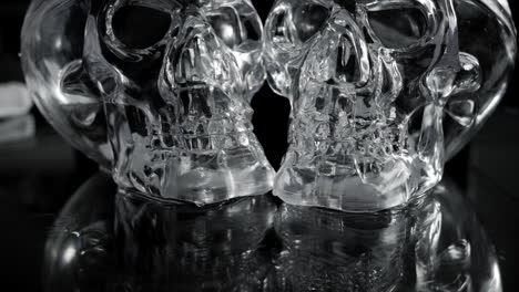 White-transparent-glass-skulls-on-black-background,-rotating-dolly-shot