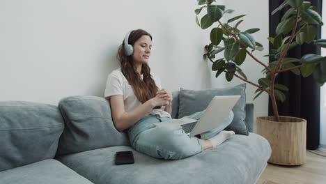 Linda-Joven-Hace-Una-Videollamada-Con-Su-Computadora-Portátil-Desde-El-Sofá-En-Casa-1