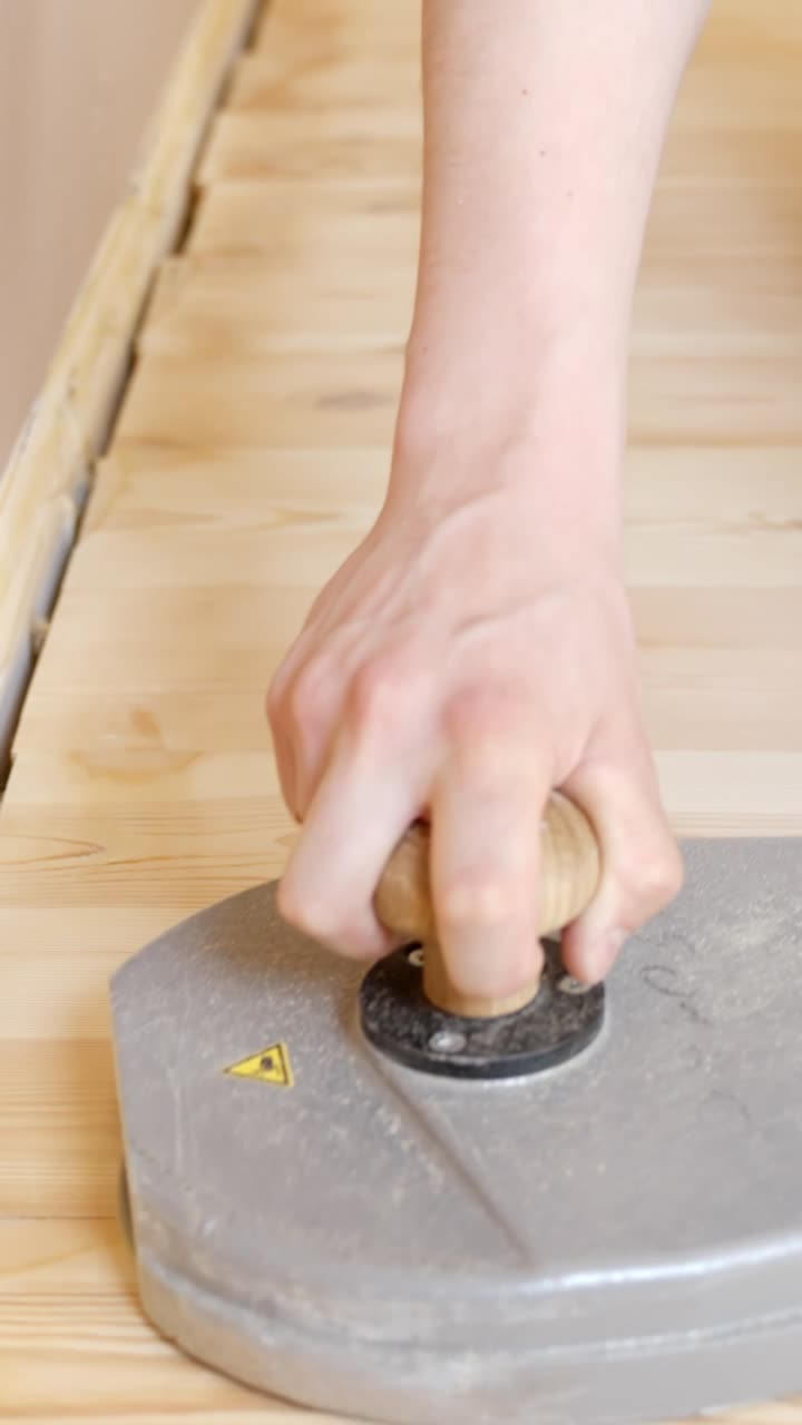 Close-up hand sanding machine tool being used to smooth and maintain wooden floors