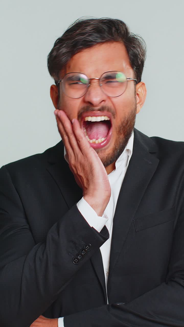 Business man touching cheek closing eyes with expression of terrible suffer from painful toothache