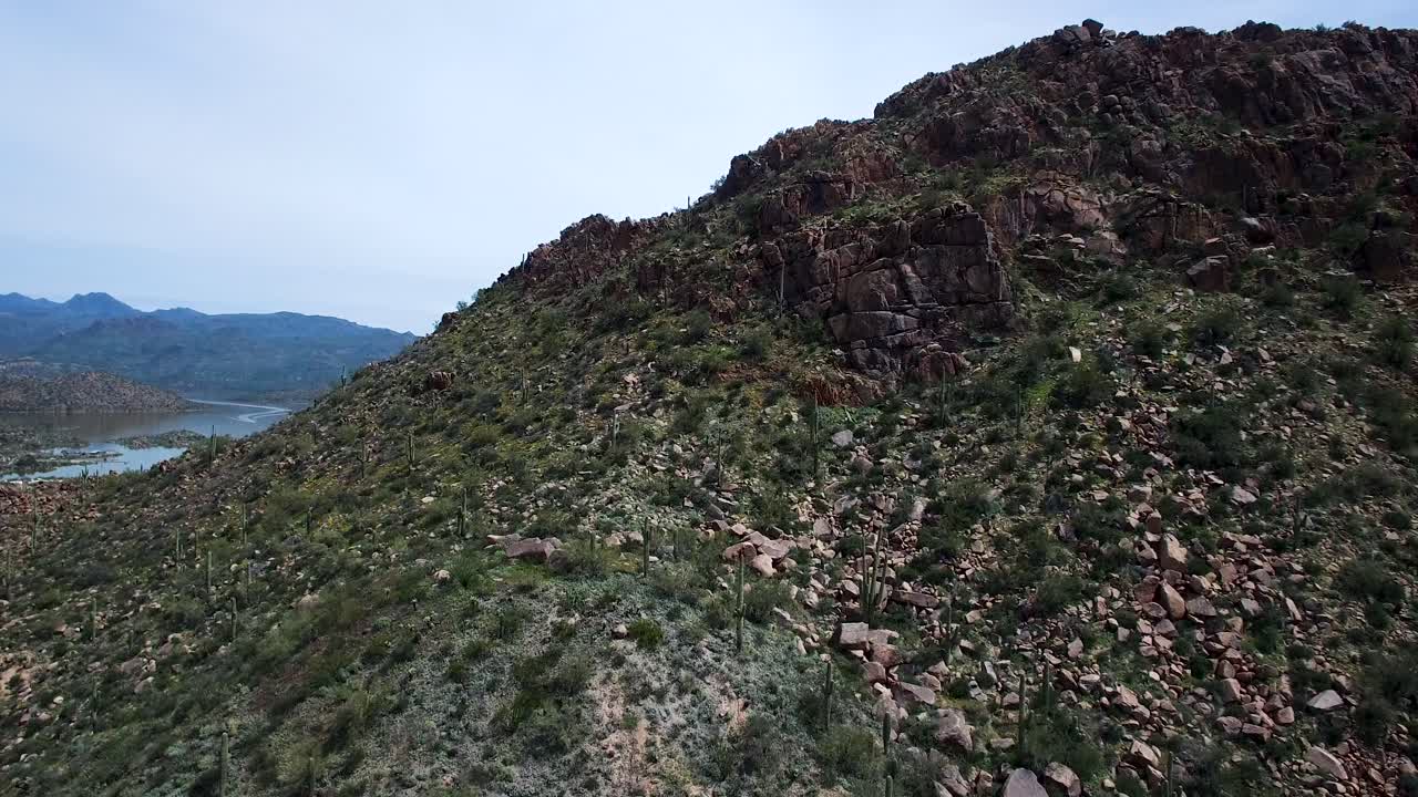 inclinación aérea hacia arriba desde la escarpada montaña del desierto para revelar el lago bartlett, el bosque nacional tonto, scottsdale, arizona