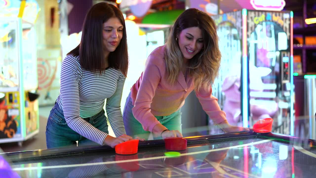 Dos mujeres jugando al hockey de aire en una sala de juegos