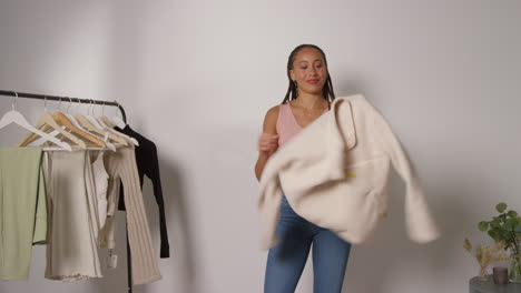 influencer femenina de redes sociales produciendo contenido generado por el usuario en el estudio probando una variedad de trajes de moda filmados en tiempo real 2