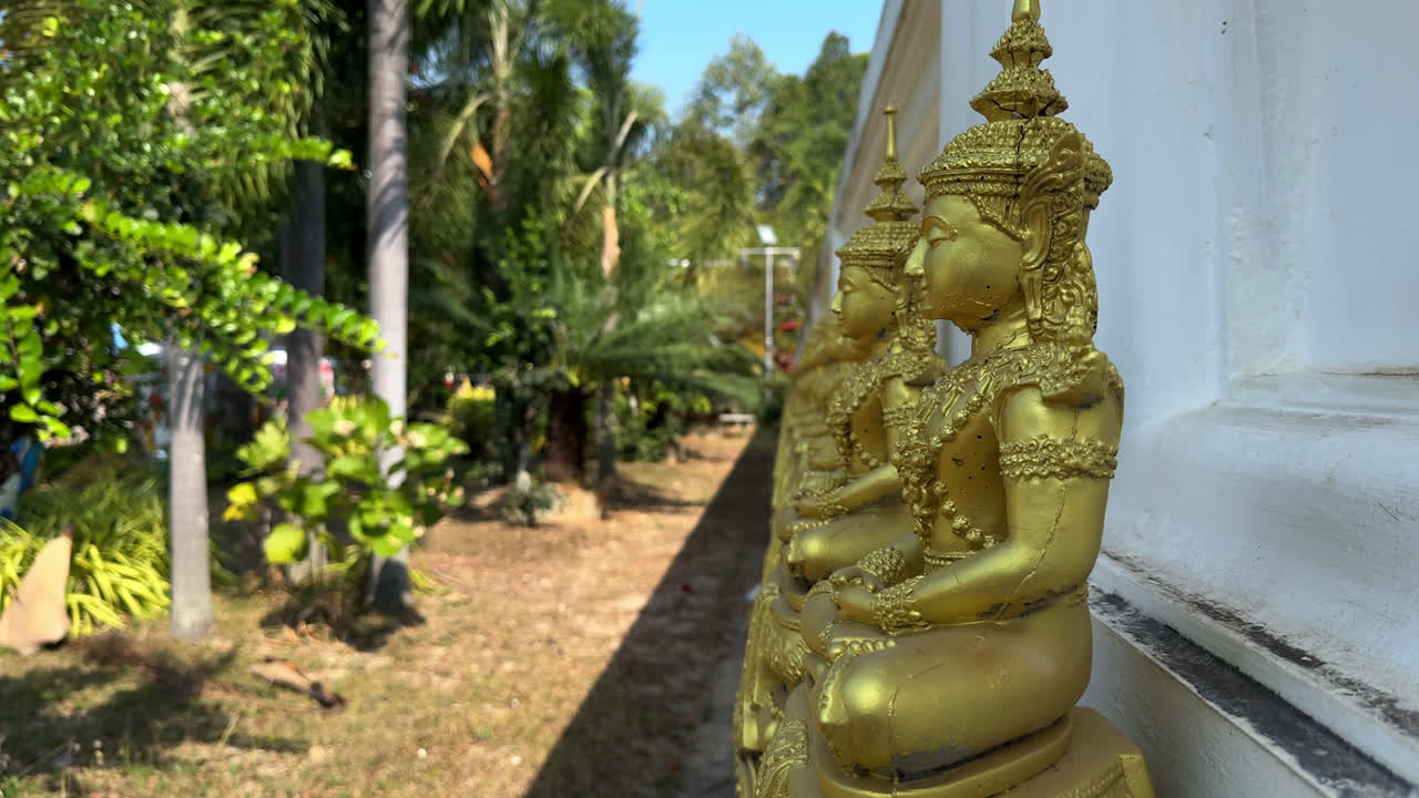 Side View Of Row Of Golden Buddha Statues Outside Wat Rong Khun Temple In Chiang Rai, Thailand. static shot