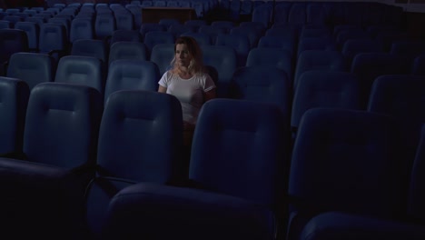 una mujer está viendo una película sola en un cine vacío.