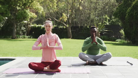 Feliz-Pareja-Diversa-Haciendo-Yoga-En-Un-Jardín-Soleado,-Cámara-Lenta