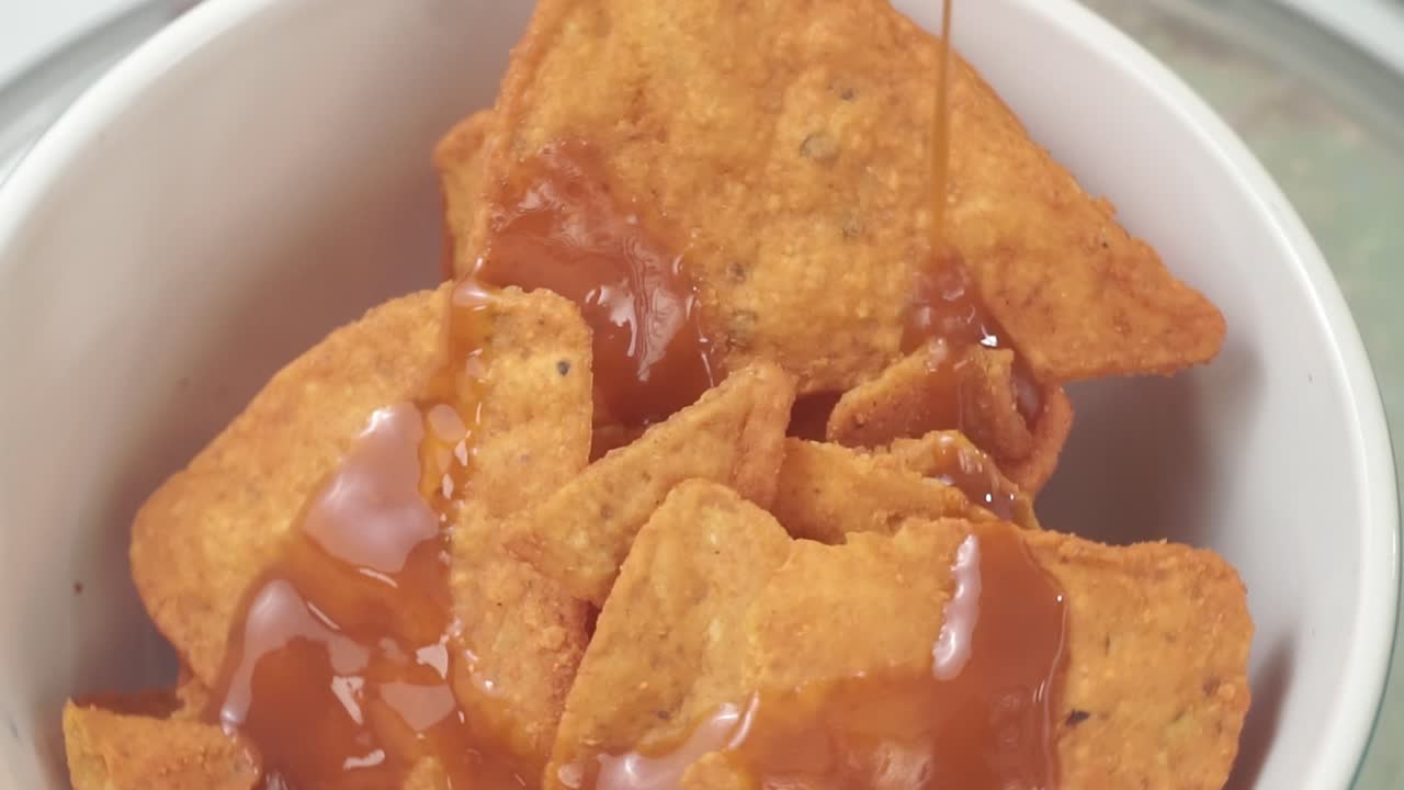 Close-up of tortilla chips with salsa pouring, snack time delight