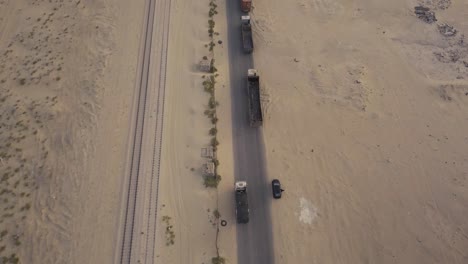 Larga-Fila-De-Camiones-En-El-Desierto-En-Un-Video-Aéreo-De-Carretera-Rota