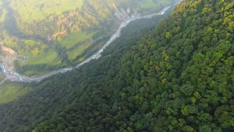 fotografía aérea de arriba hacia abajo de las verdes montañas exuberantes y el río que fluye en el valle al amanecer en nepal