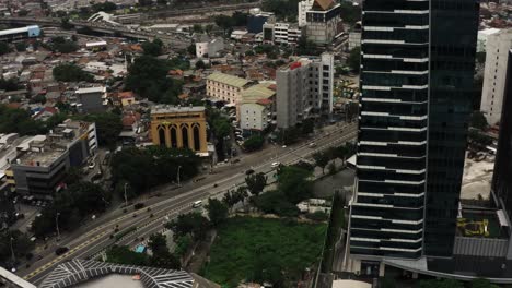 Toma-Aérea-Inclinada-Hacia-Abajo-Del-Tráfico-En-La-Autopista-En-La-Ciudad-De-Yakarta-Durante-El-Día-Nublado,-Indonesia