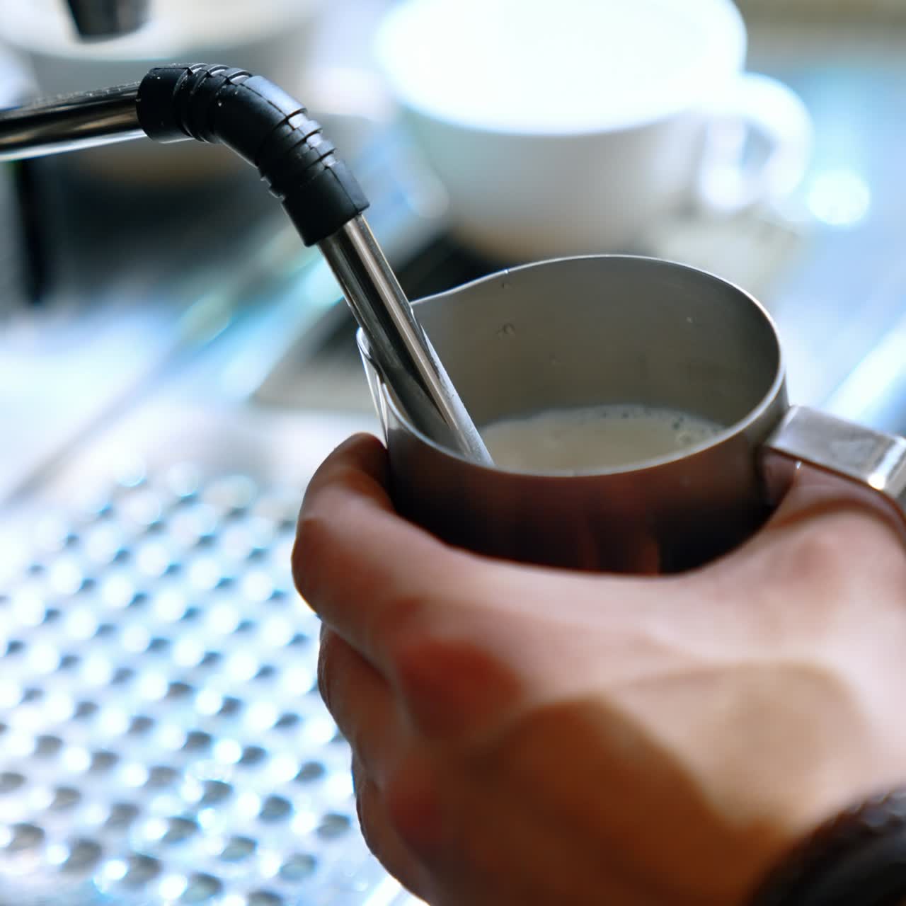 Coffee making machine close up. Male hands hold the pot filling it with hot milk. Close up. Vertical screen. Blurred backdrop